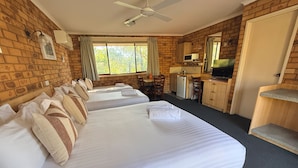 A hotel room with two beds, a kitchenette, a television, and a ceiling fan. - Ocean View Motor Inn (Merimbula)
