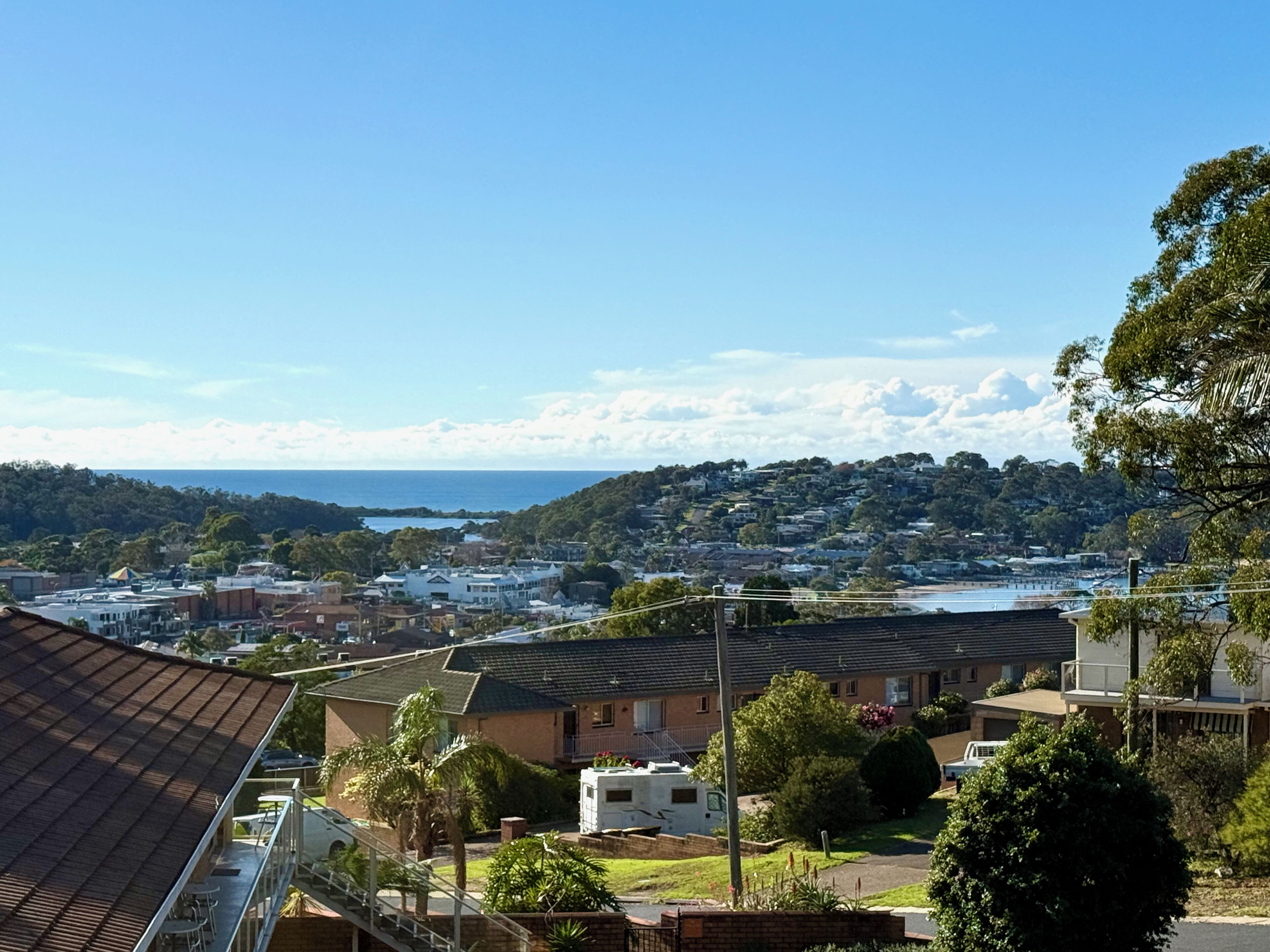 Un quartiere residenziale con case, cielo sereno e vista sullo sfondo del mare.