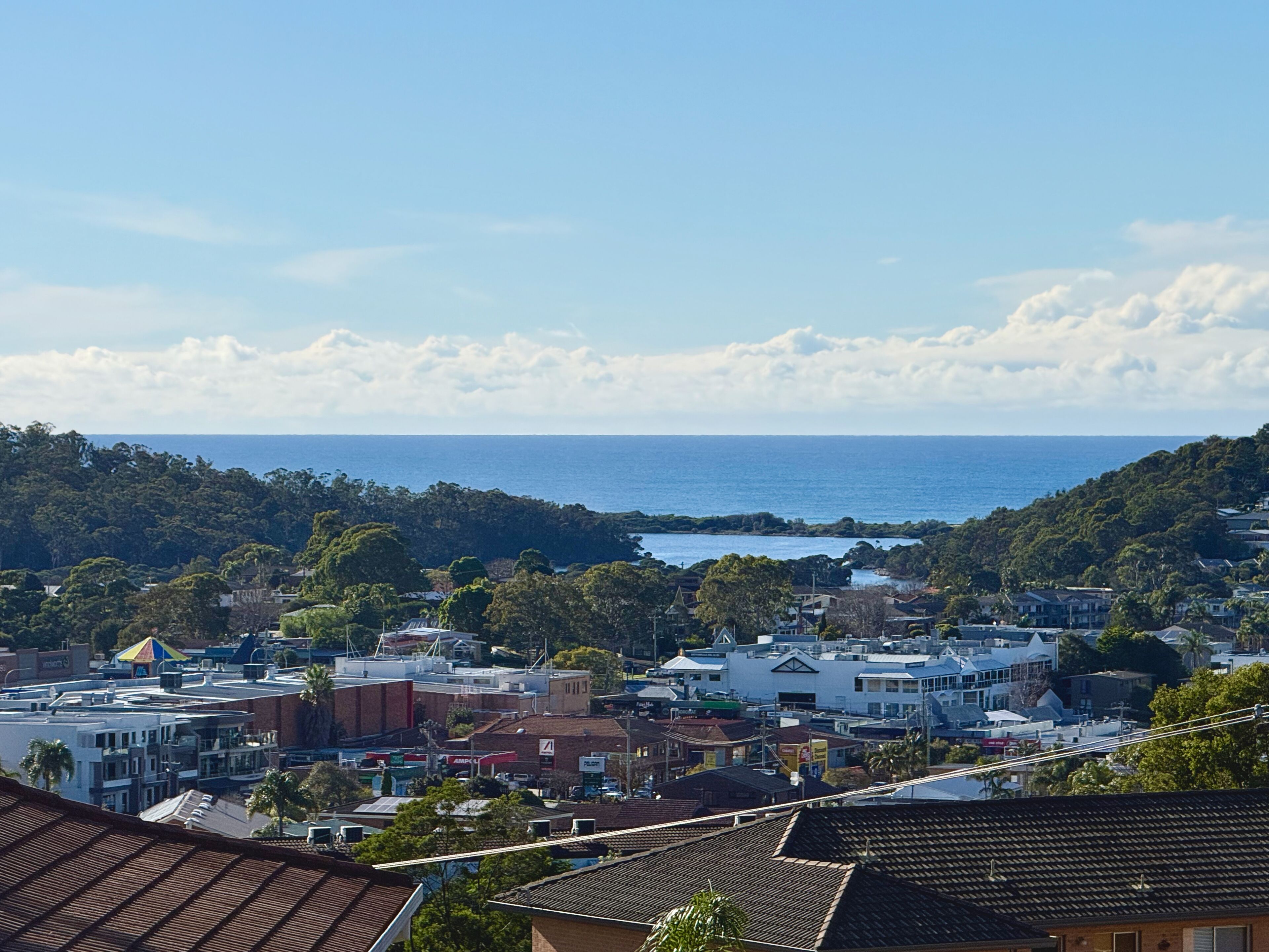 A coastal town with buildings, a view of the sea, and a hilly landscape.