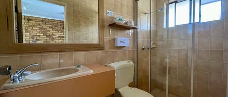 Un baño con lavamanos, inodoro y ducha con mampara de vidrio.