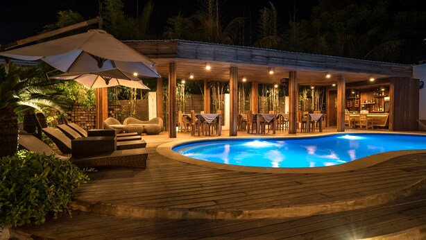 A poolside area with wooden deck, lounge chairs, and umbrellas. - Villa Nero (Gili Trawangan)