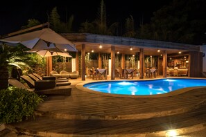 A poolside area with wooden deck, lounge chairs, and umbrellas. - Villa Nero (Gili Trawangan)