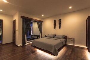 Un dormitorio con una cama grande, una mesita de noche, una ventana con cortinas y una puerta.