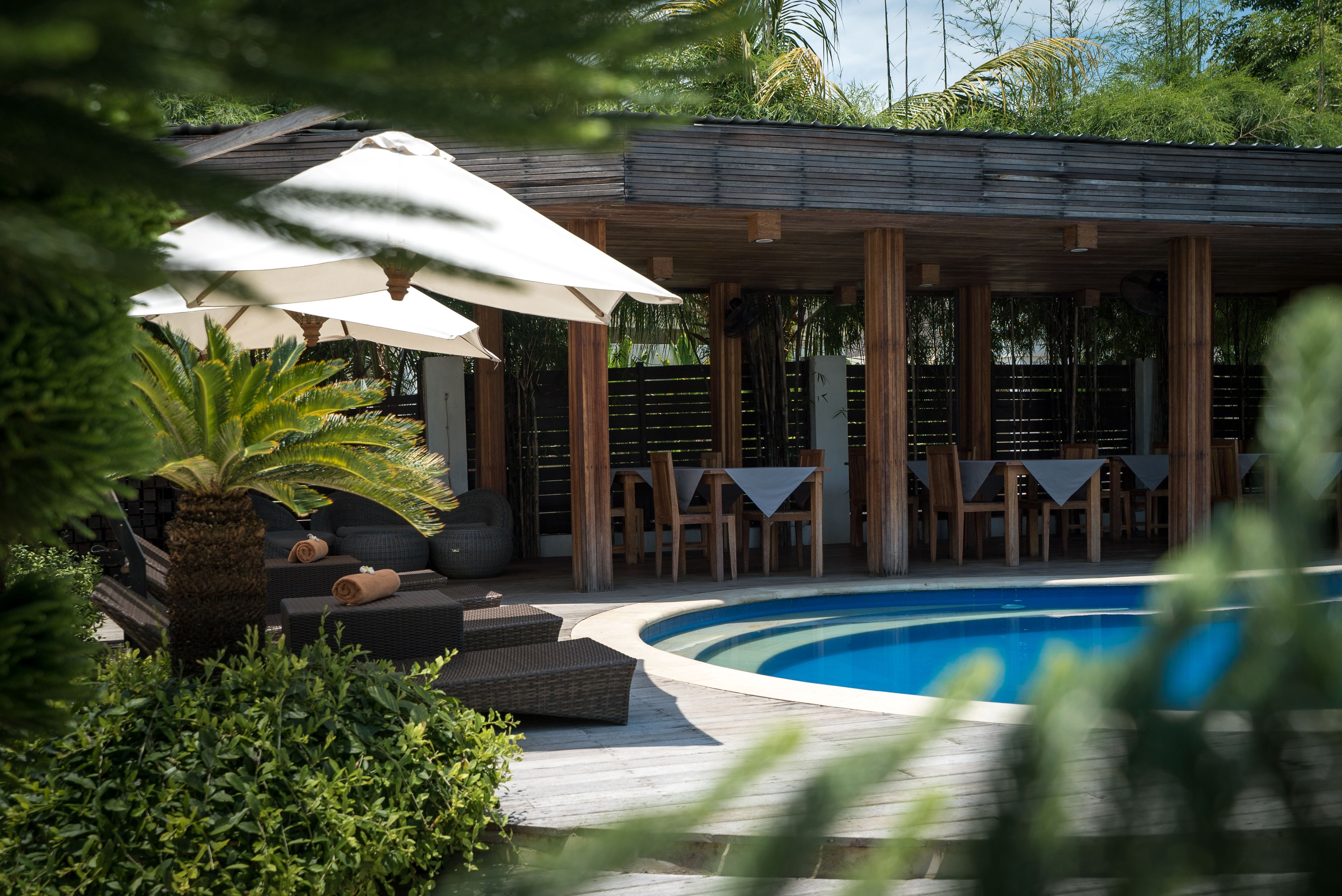 A poolside area with a wooden deck, lounge chairs, and umbrellas.