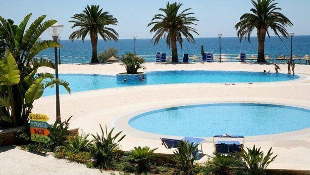Zona de piscina amb palmeres, gandules i un cartell informatiu sobre els serveis.