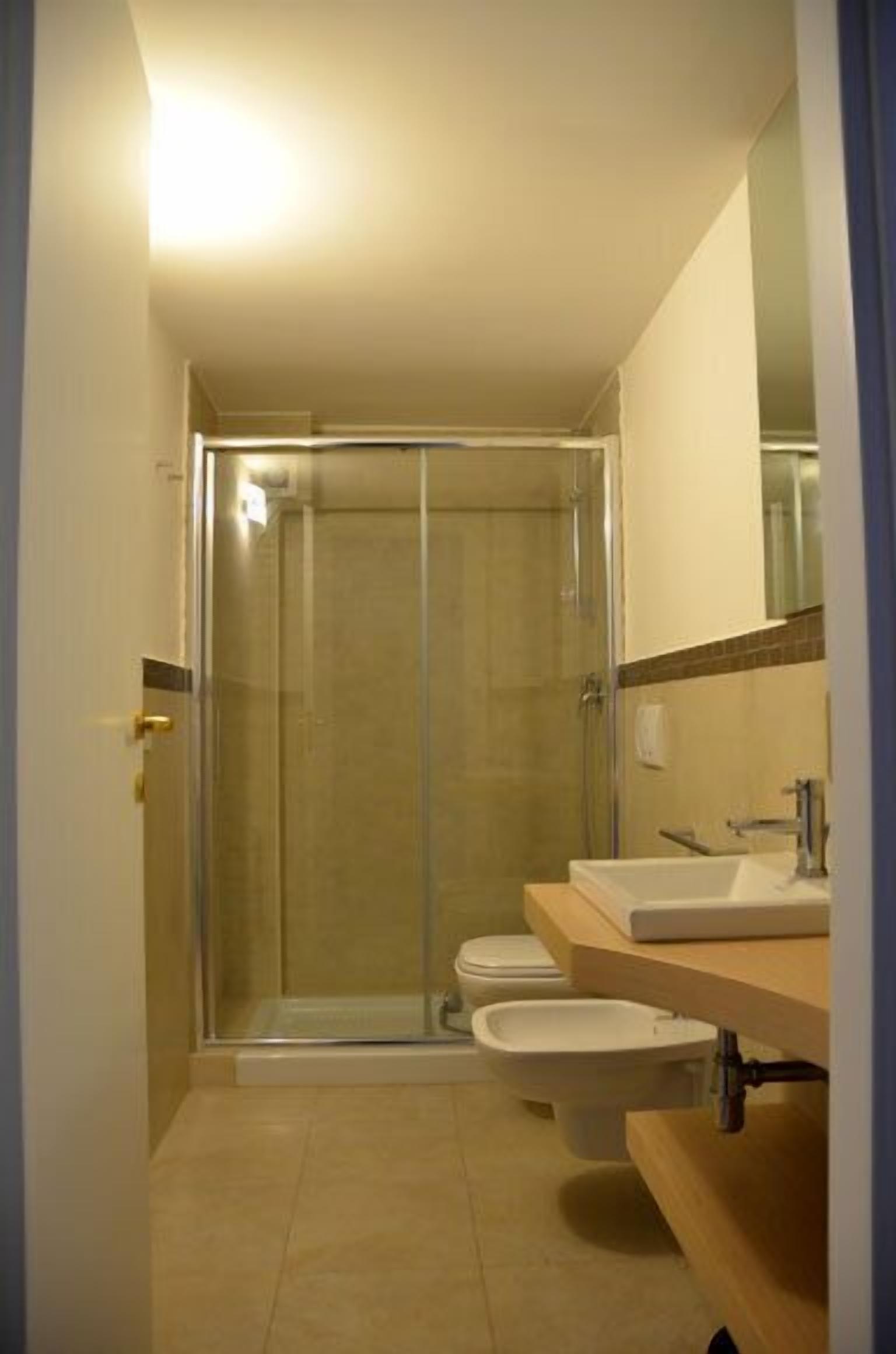 Un baño con ducha de vidrio, inodoro y lavabo con espejo.
