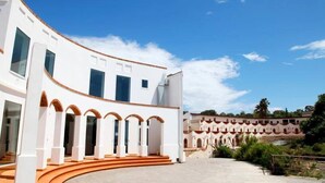 Edifici modern amb façana corba, diverses finestres i una sèrie d'arcs que condueixen a un pati central.