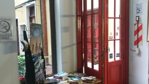 A small room with a wooden desk and chair, a red door, and a window. - Santino Recoleta (Buenos Aires)