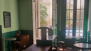 A restaurant interior with a wooden table and chairs, a chalkboard menu, and large windows with a view of the street. - Santino Recoleta (Buenos Aires)