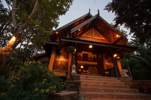 A wooden cabin with a porch, steps leading up to it, and a small garden area with yellow flowers.