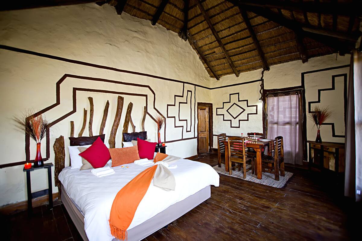 Een slaapkamer met een groot bed, houten meubels en een rieten dak.