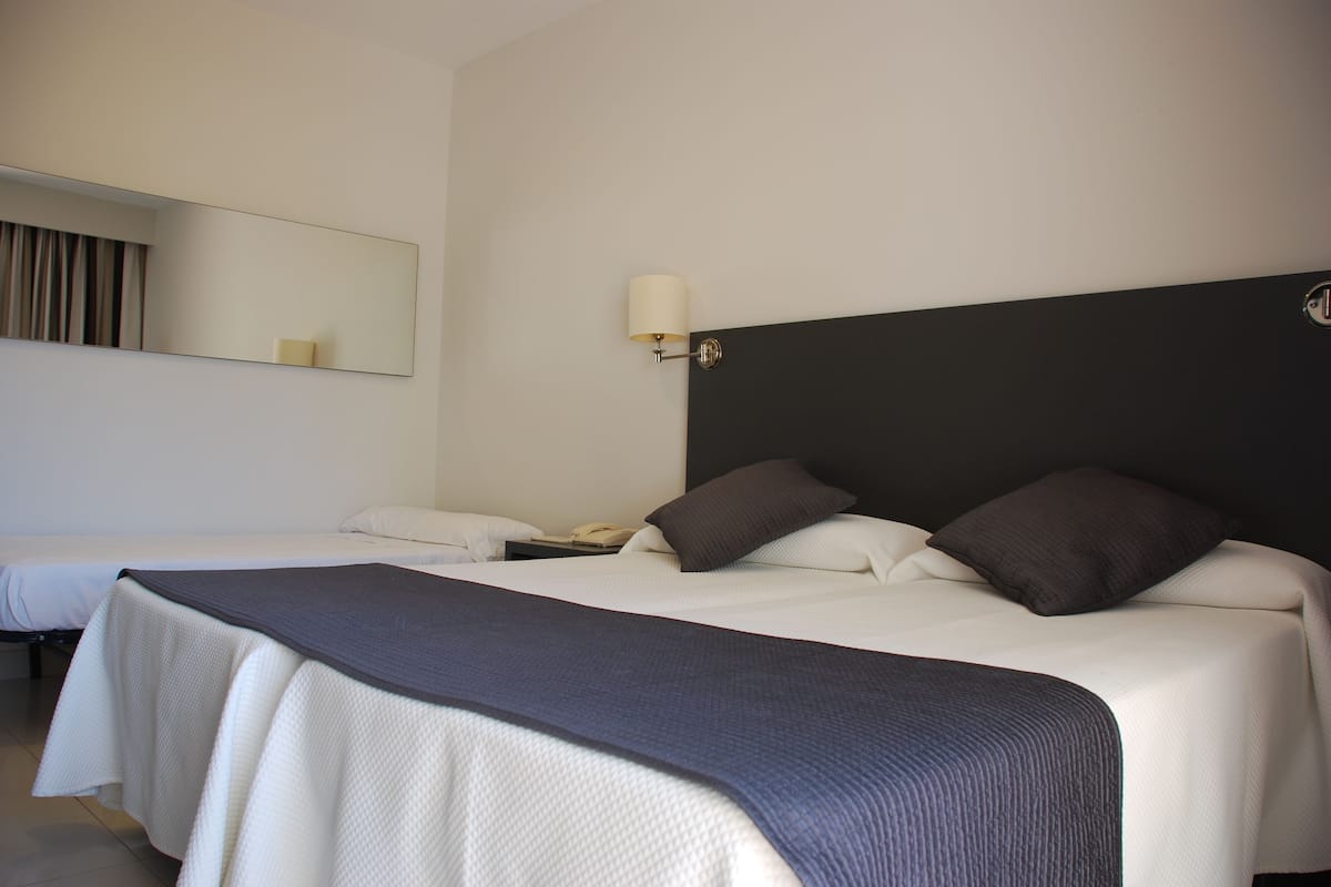 Une chambre d’hôtel avec deux lits, un grand miroir, une lampe de chevet et un téléphone.