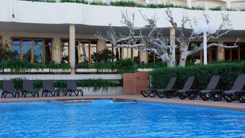 Een seizoensgebonden buitenzwembad en ligstoelen