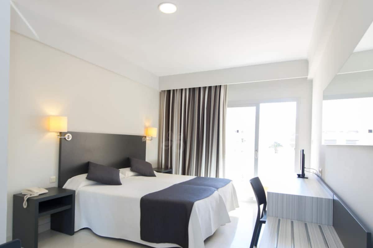 Une chambre d’hôtel moderne avec un grand lit, des lampes de chevet, un bureau et une chaise.