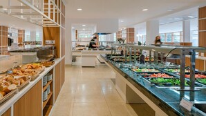Zona de bufé con diversas opciones de comida, incluyendo pan, ensaladas y otros platos.