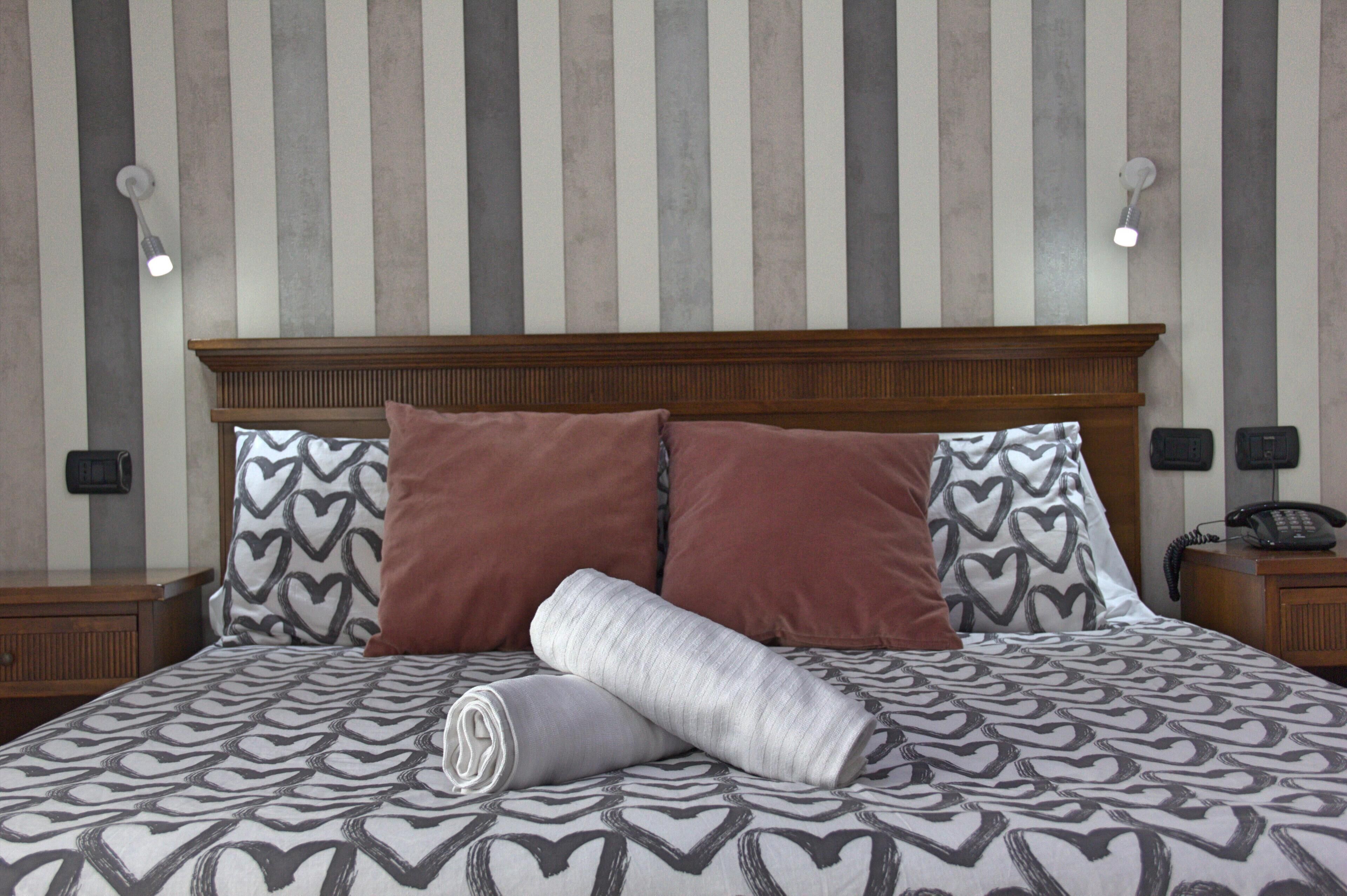 A neatly made bed with patterned bedding, a wooden headboard, and two bedside lamps.