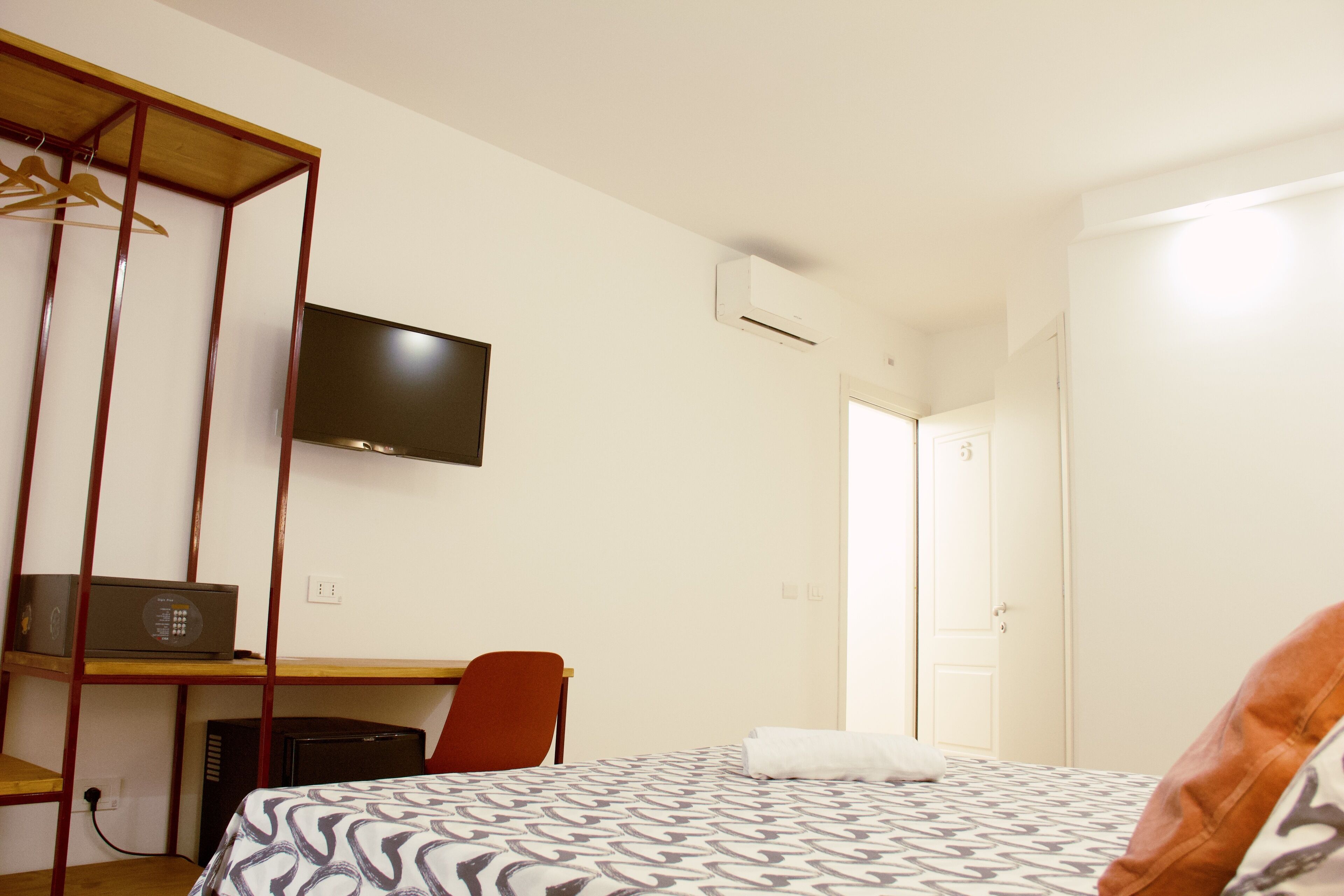 A hotel room with a bed, a desk, a chair, a television, and a wardrobe.