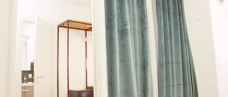 A bedroom with a four-poster bed, a bedside table, and a wardrobe.