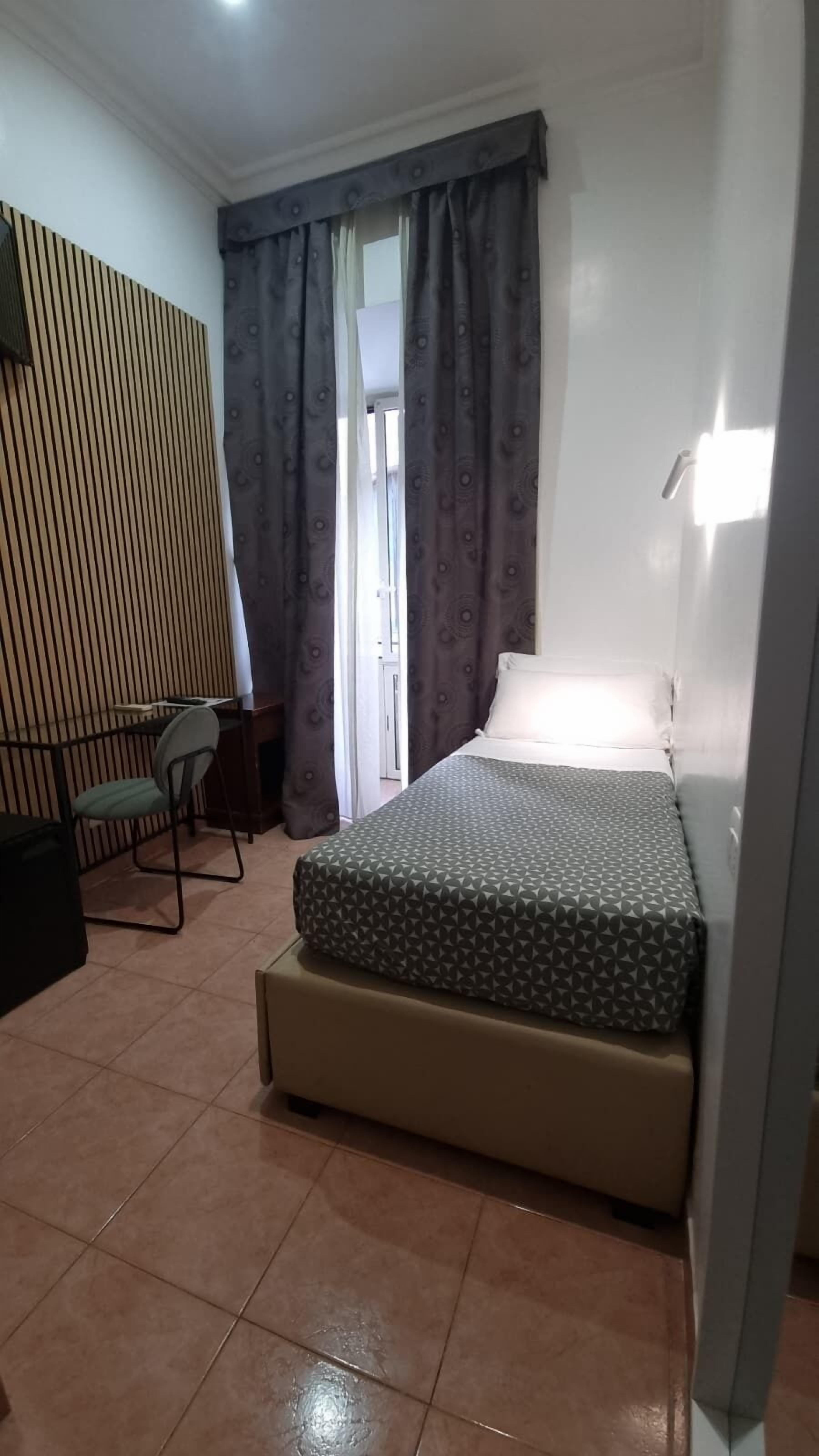 Ein kleiner, gemütlicher Raum mit Bett, Schreibtisch und Stuhl.