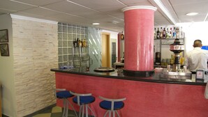 Zona de bar con mostrador rojo, tres taburetes azules y un pilar rosa.