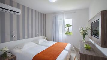 Ein Hotelzimmer mit Bett, Nachttisch und Schreibtisch mit Spiegel.