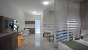 Una habitación de hotel moderna con una cama, televisión, escritorio y kitchenette.