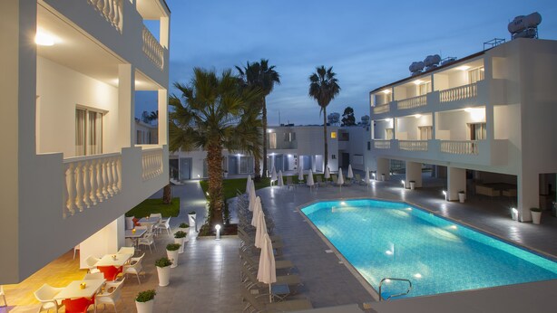 A hotel with a swimming pool, outdoor seating, and multiple balconies. - Princessa Vera Hotel Apartments (Paphos)