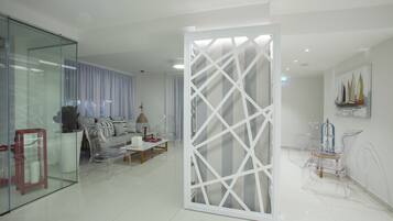 Een moderne woonkamer met een glazen scheidingswand, een bank, een salontafel en een transparante stoel.