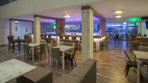 A spacious restaurant with multiple dining areas, wooden flooring, and a view of the street through large windows. - Princessa Vera Hotel Apartments (Paphos)