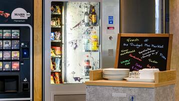 A vending machine with Mars drinks and a chalkboard menu listing items like sausage, pizza, and cola.