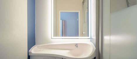 A bathroom with a white sink, a mirror, and a towel hanging on a rack.