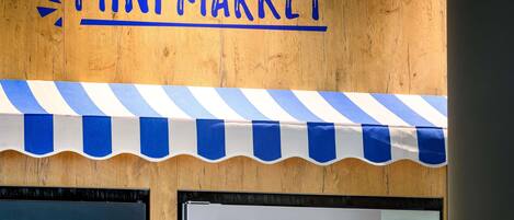 A wooden wall with a blue and white striped awning and the text 'MINI MARKET' above it.