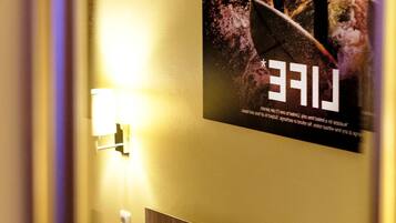 Ein Hotelzimmer mit einem Bett, einer Wandleuchte und einem Poster, das einen Surfer auf einer Welle zeigt.