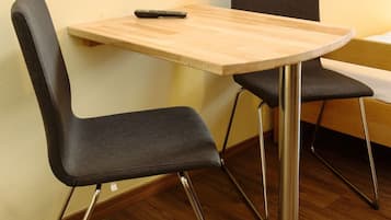 Een lichte, moderne kamer met een houten tafel en twee zwarte stoelen met metalen poten.