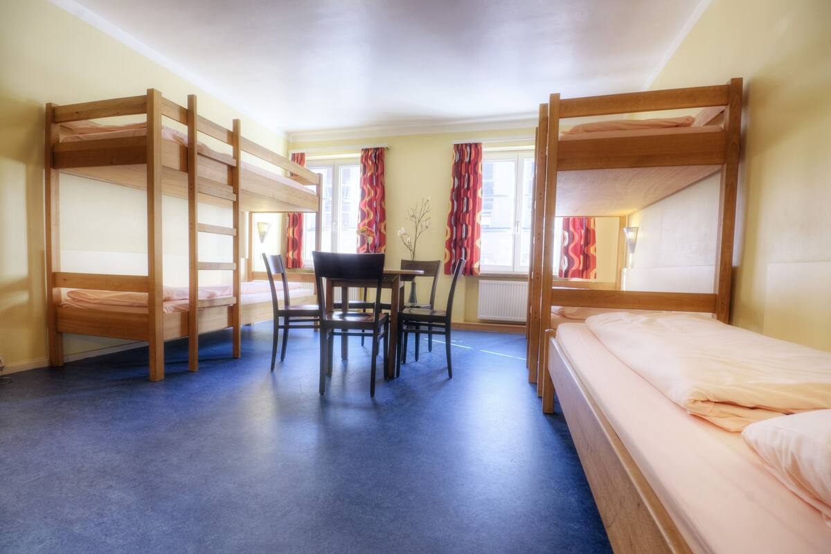 Une chambre de dortoir avec des lits superposés, un bureau et une chaise.