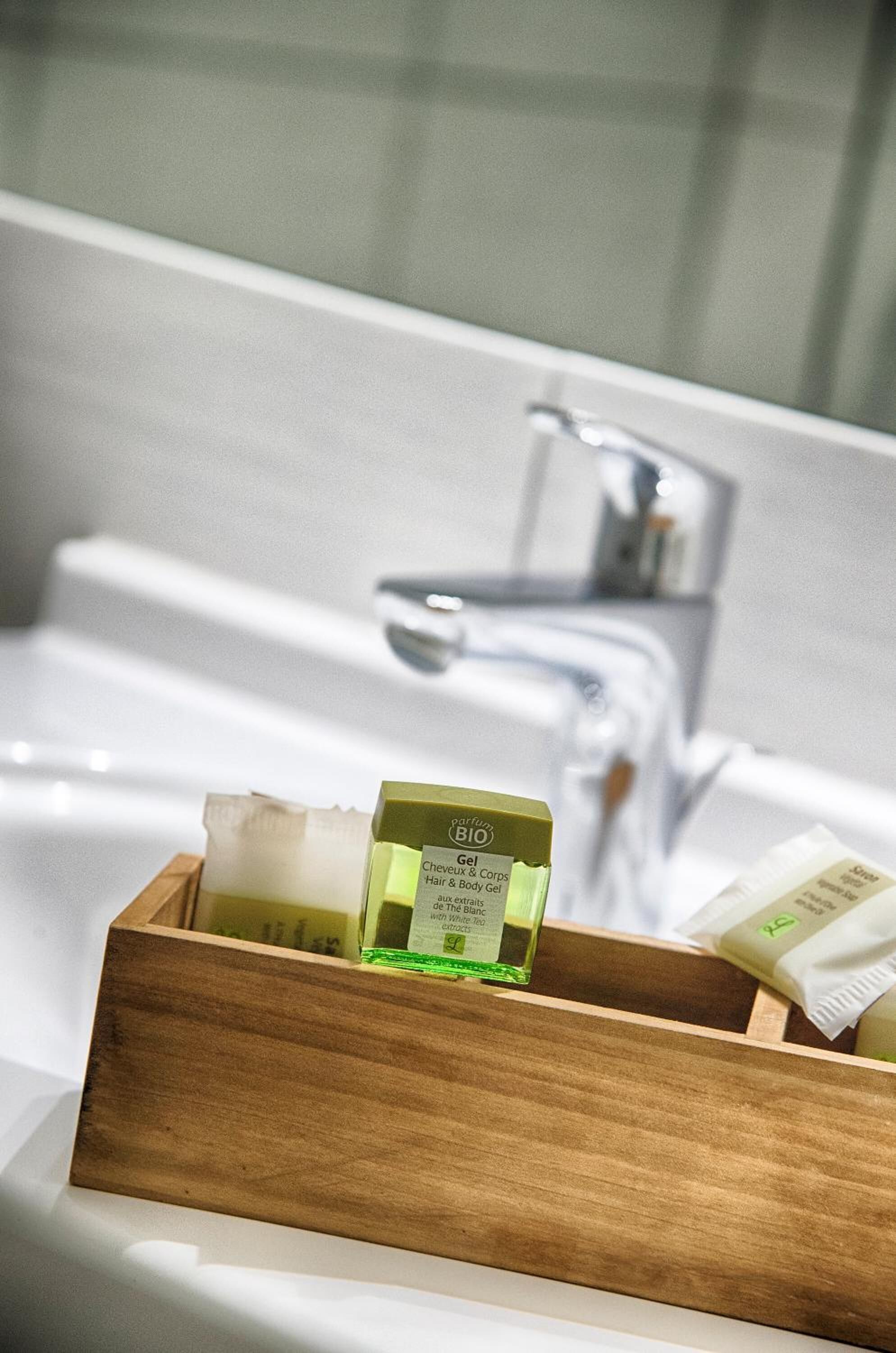 A wooden tray with a bottle of Cheveaux & Corps body gel and a bar of soap in a bathroom setting.