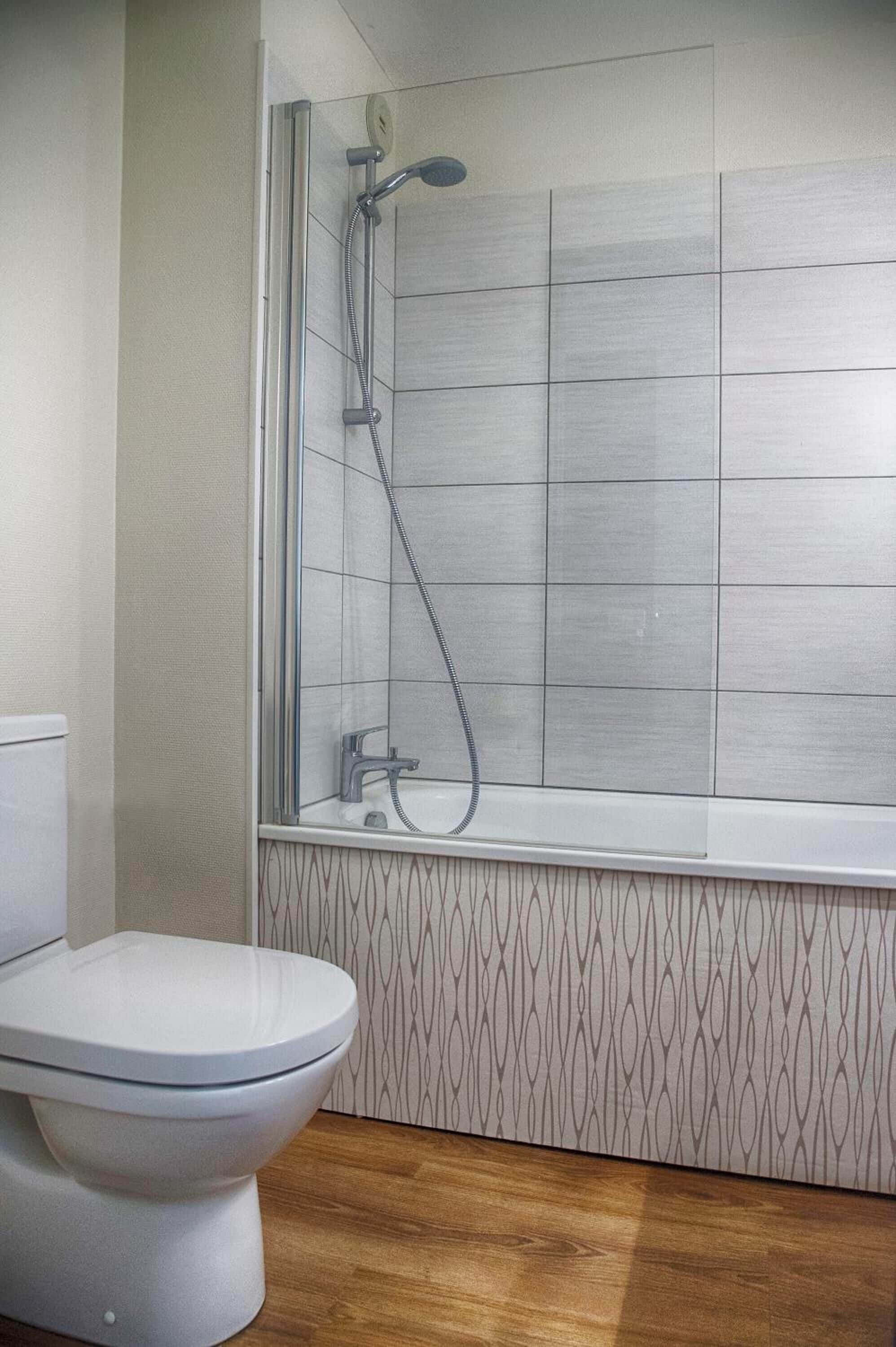 Et badeværelse med brusebad, toilet og tapet.