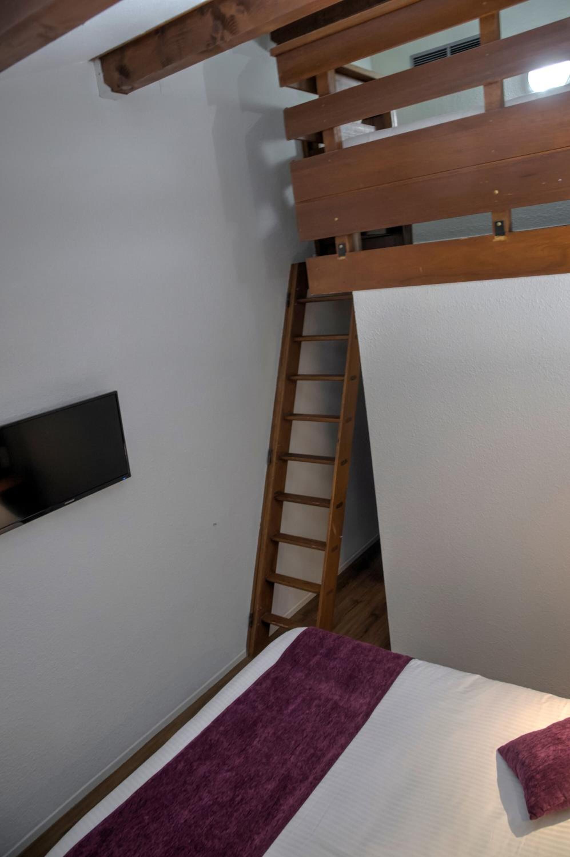 Quarto com beliche, escada, TV de tela plana e manta roxa.