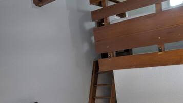 A bedroom with a bunk bed, a ladder, a flat-screen TV, and a purple throw blanket.