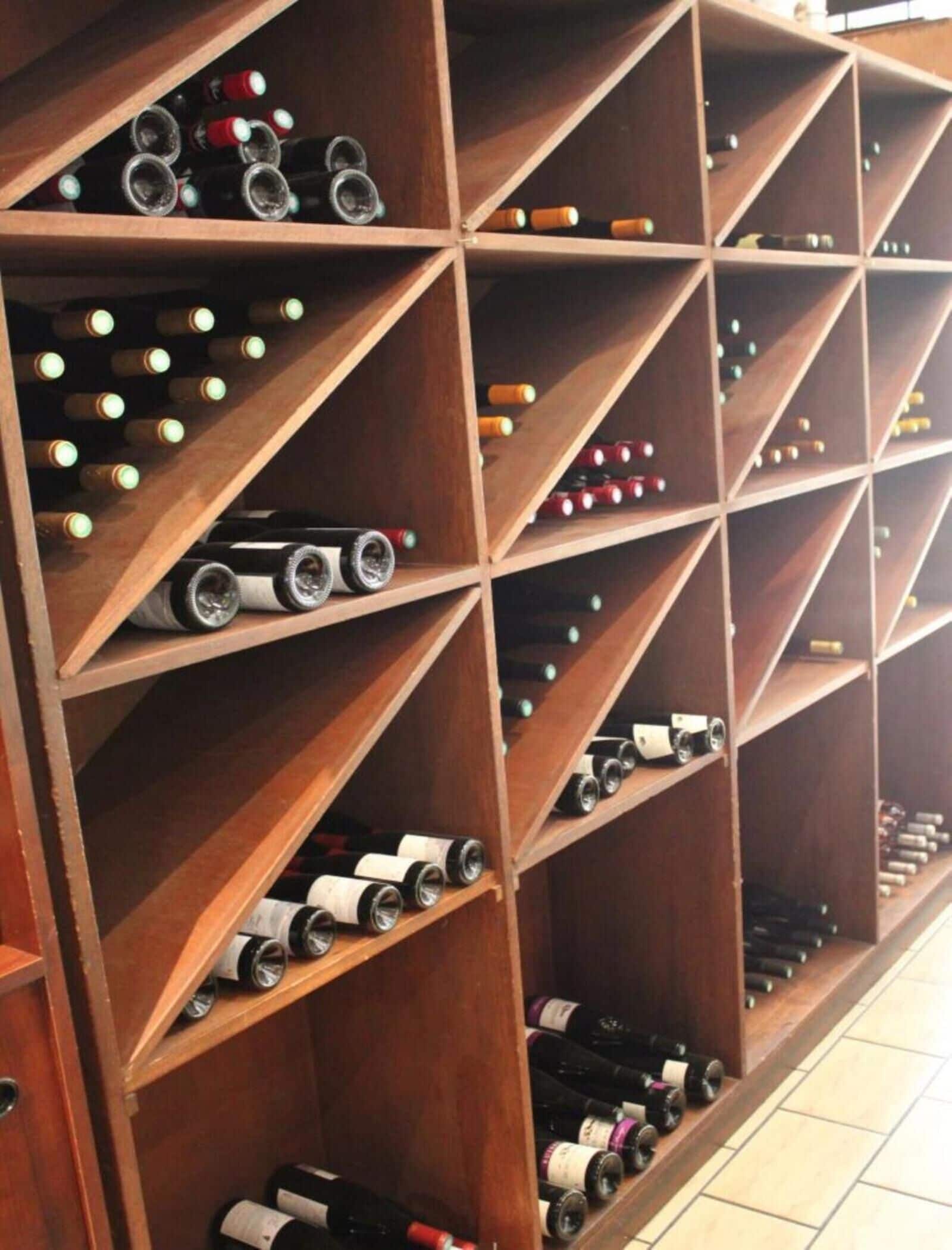 A wine rack with multiple shelves holding various bottles.