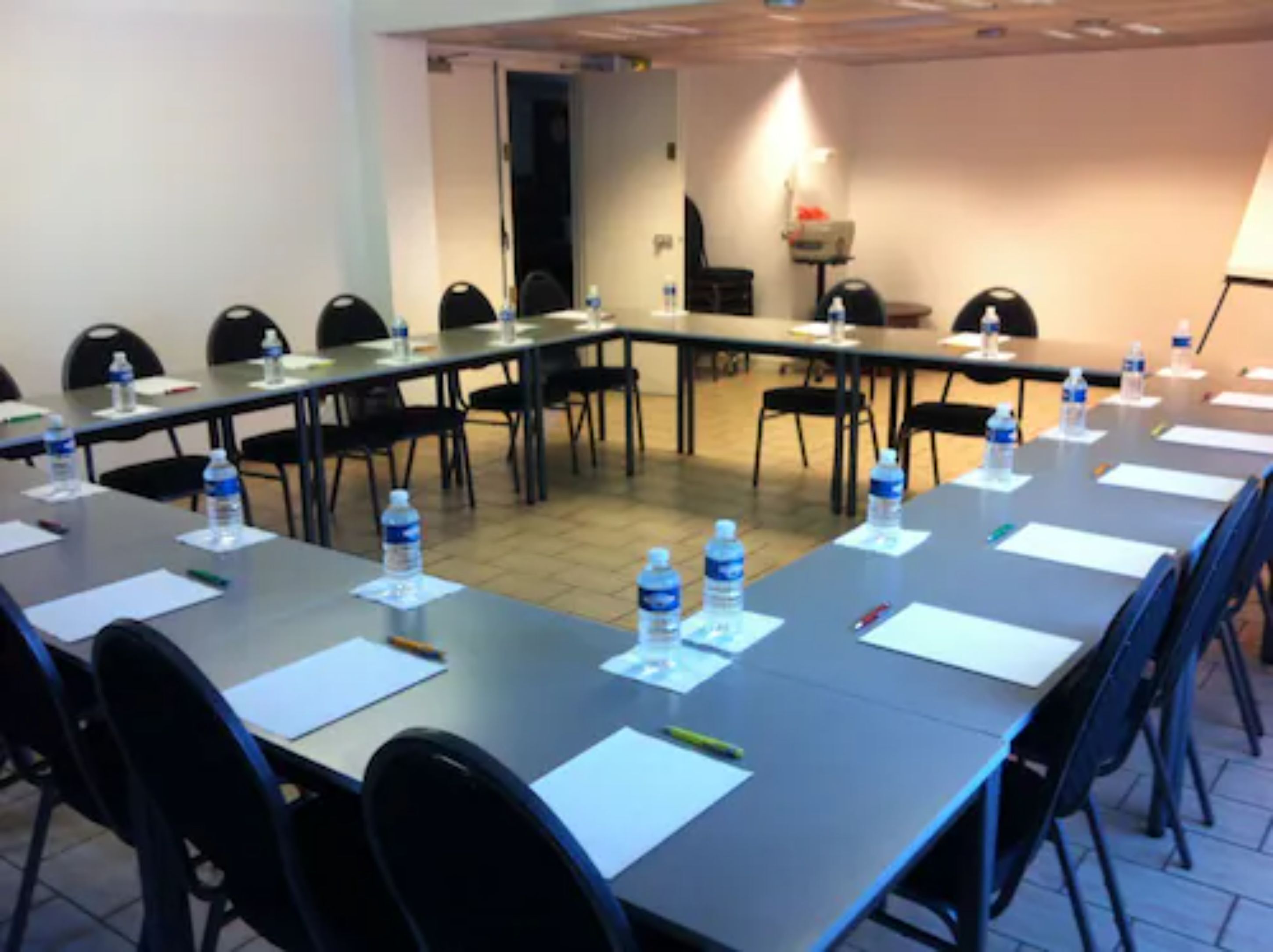 A conference room with long tables, chairs, water bottles, and papers.