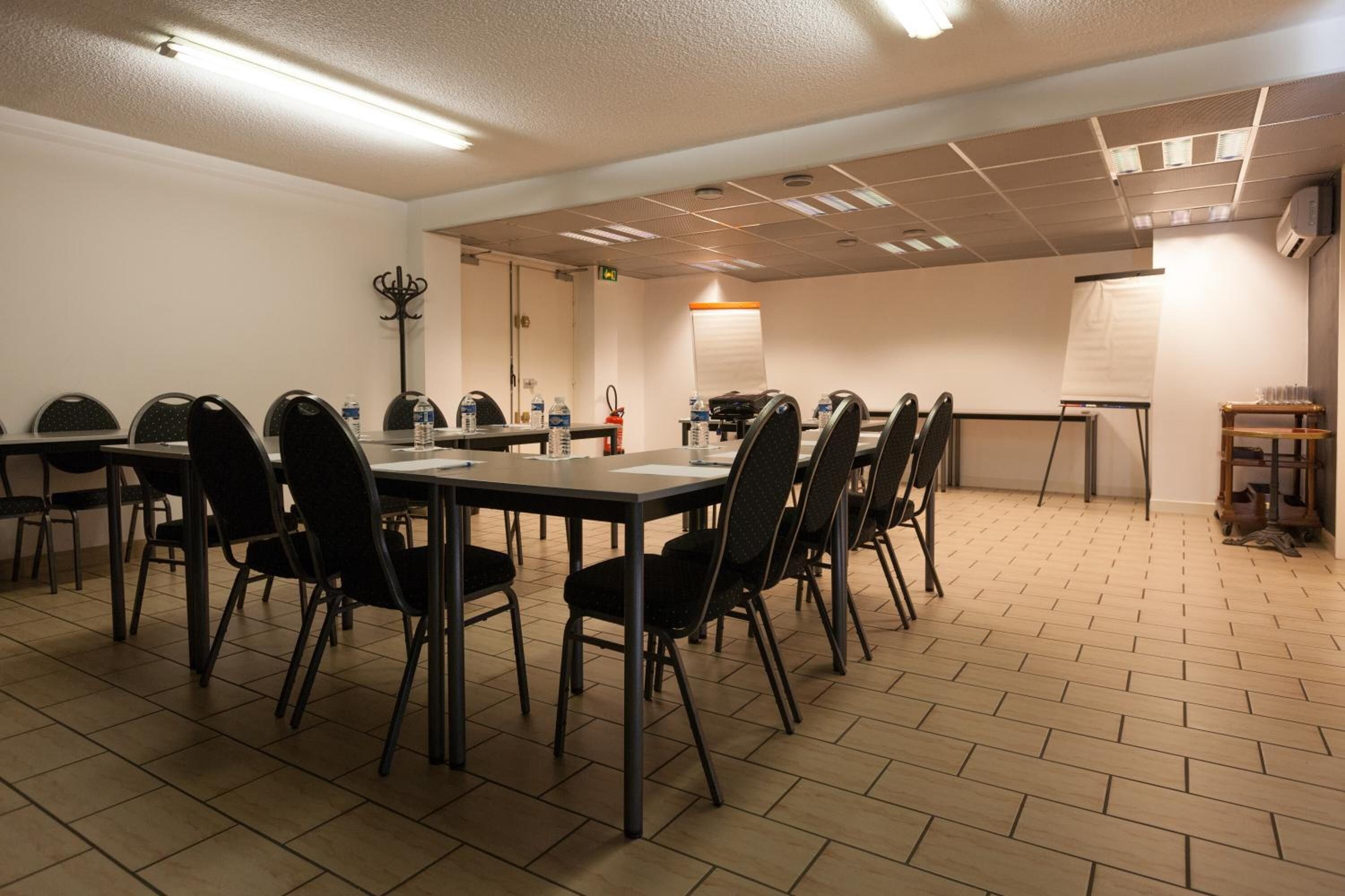 Uma sala de conferências com uma mesa comprida, cadeiras, um quadro branco e um projetor.