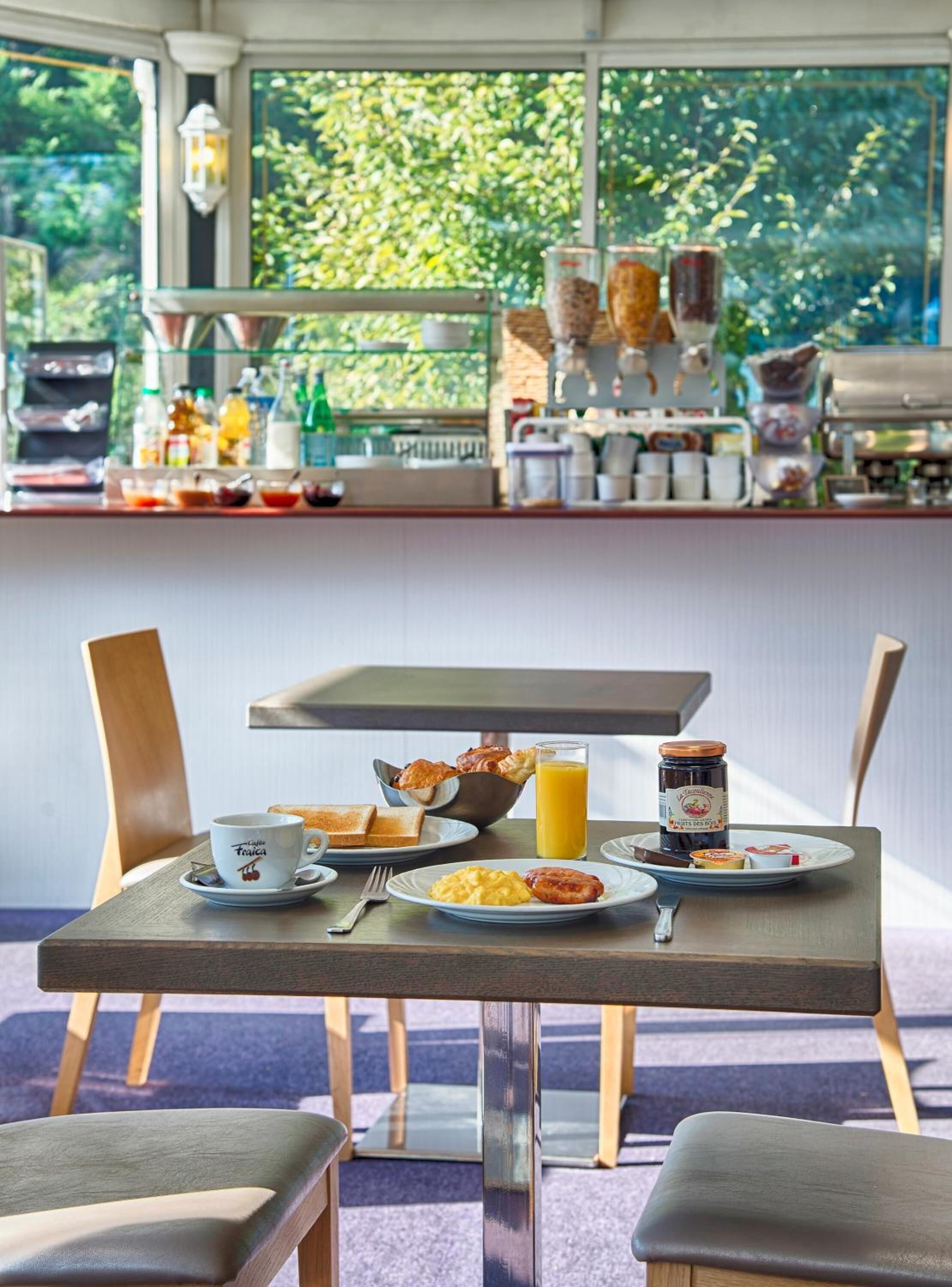 Un desayuno con una mesa, sillas y vistas al exterior.