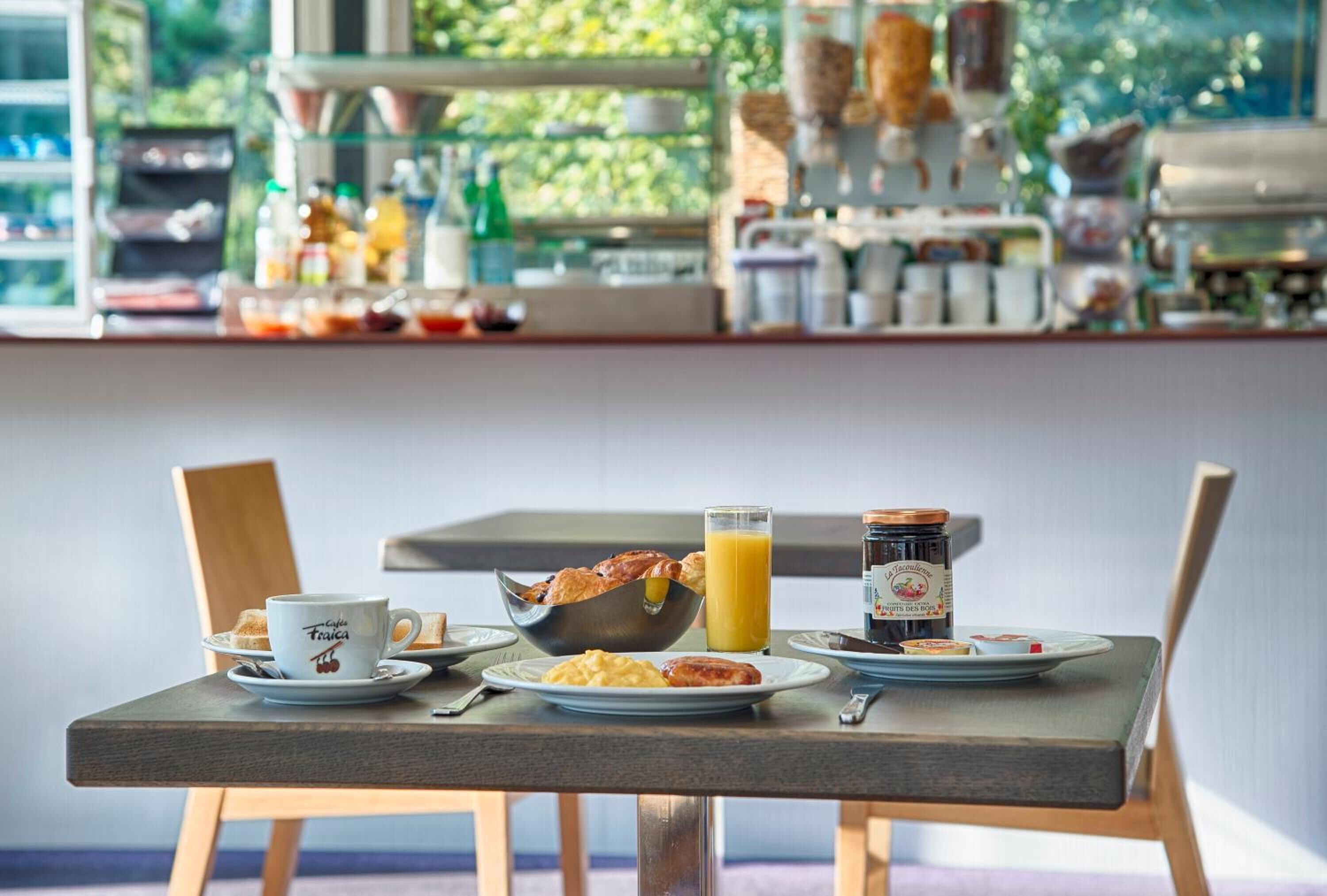 Una mesa de desayuno con una taza, un bol, un plato y zumo.