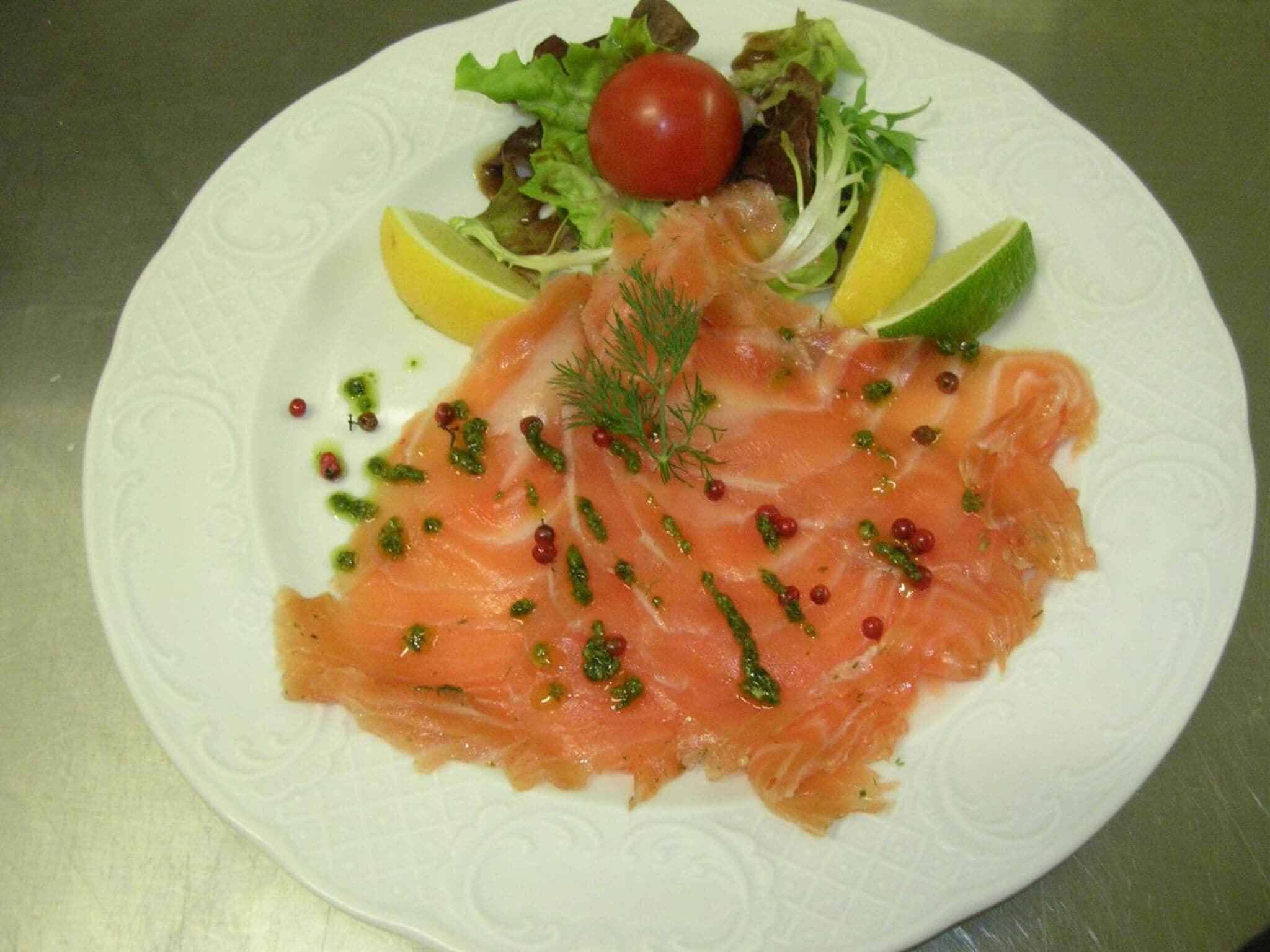 A plate of smoked salmon with lemon slices, capers, and a garnish of dill.