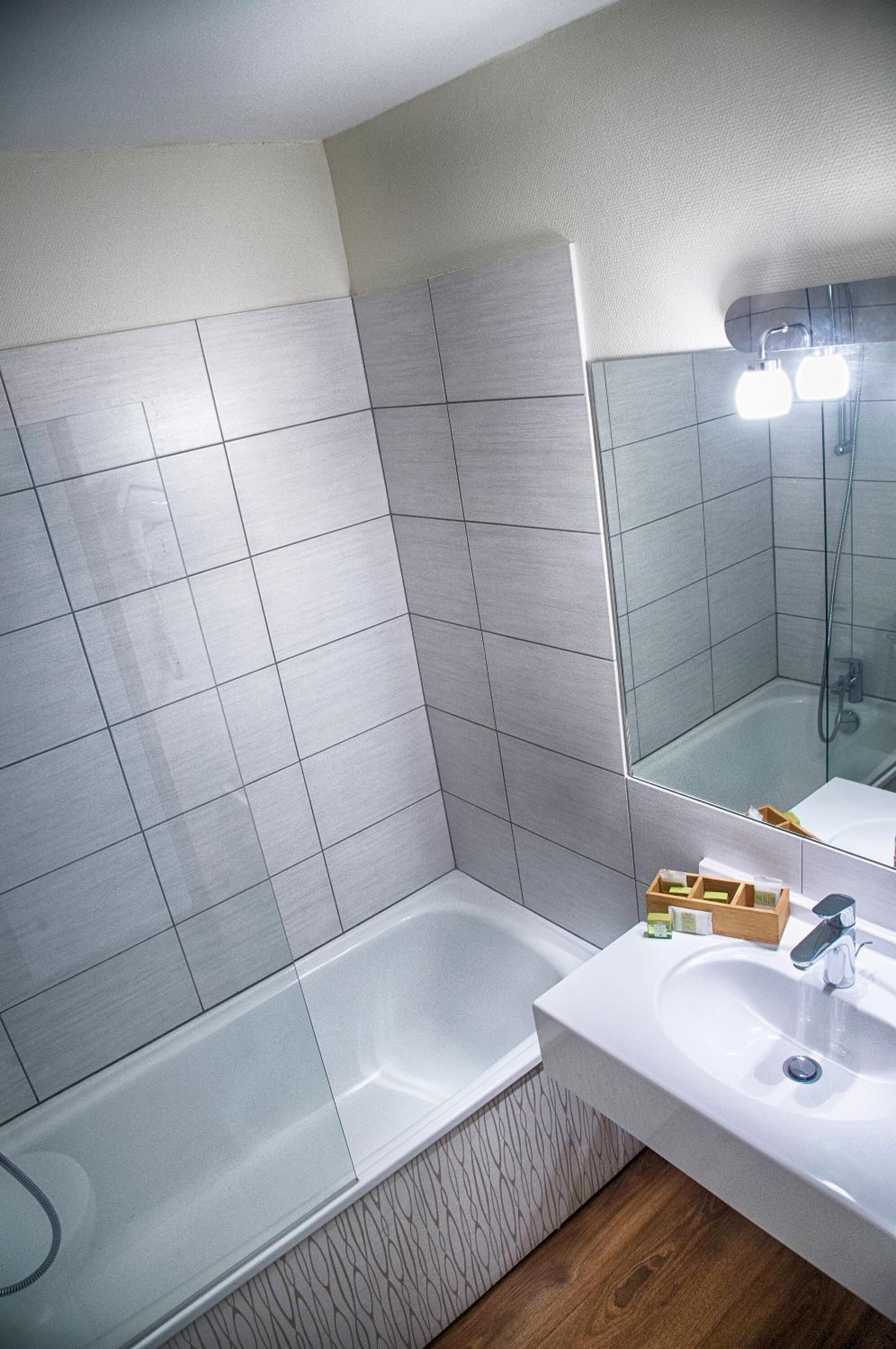 A modern bathroom with a bathtub, a sink, and a mirror.