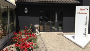Entrada de un hotel con fachada negra, puerta de cristal y un letrero que indica que es un restaurante.