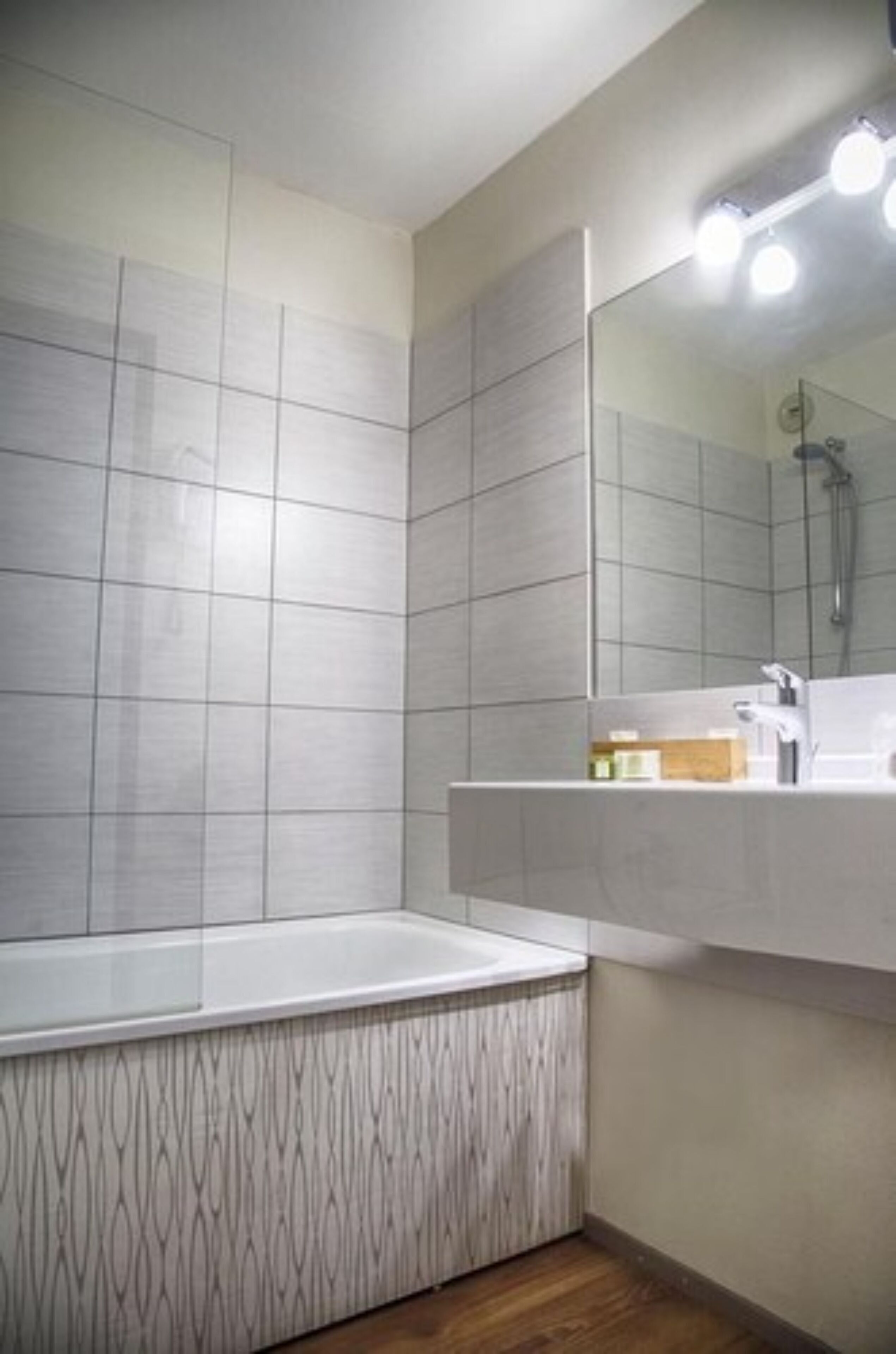 Ein modernes Badezimmer mit einem großen Spiegel, einer Badewanne und einem Waschtisch.