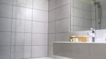 A modern bathroom with a large mirror, a bathtub, and a vanity with a sink.
