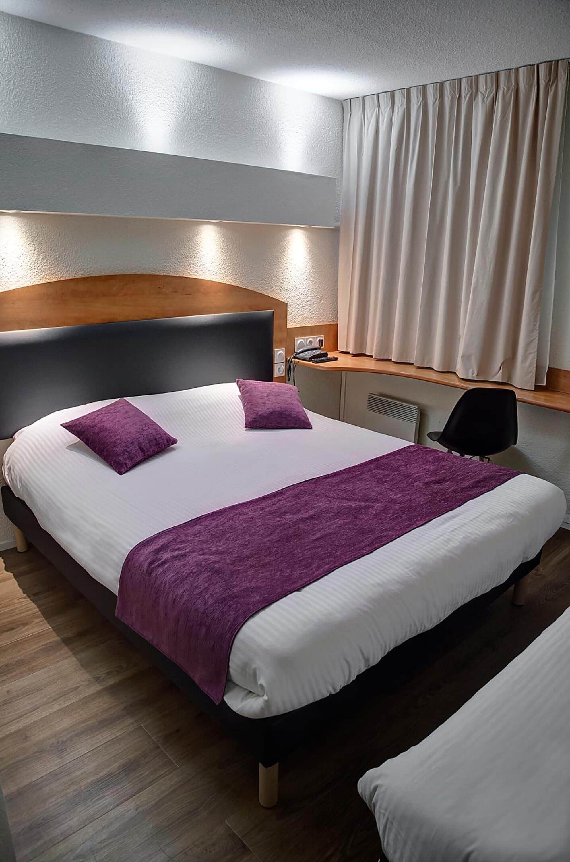Hotellihuone, jossa on sänky, työpöytä ja tuoli.